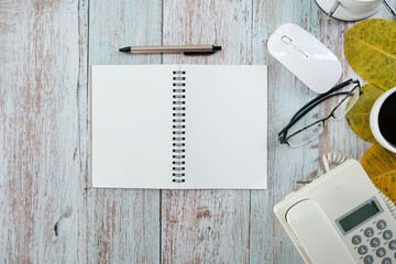 Poster - Blank notebook sheet sits on top of a wood office work table, with a laptop computer, a cup of coffee, and supplies. Flat lay, top view with copy space.
