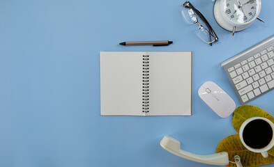 Wall Mural - Blank notepad with a pen rests on an office desk table, surrounded by computer equipment and various papers. flat lay, top view, money and banking background