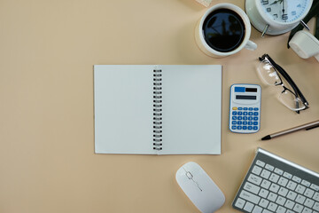 Poster - Blank notebook page is on top of wood office desk table with laptop computer, cup of coffee and supplies. Top view with copy space, flat lay.
