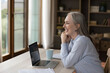 © fizkes - Cheerful happy mature business lady looking at window away from home workplace, smiling, laughing, sitting at table, laptop, papers, enjoying job success, online work chat