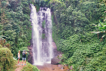 Wall Mural - Tropical traveling. Couple of travelers enjoying waterfall view.