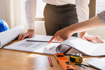 Builder team, hand of asian, caucasian young engineer, architect two man are discussing construction, use laptop computer follow project to build an industrial plan at site. Engineering worker people.