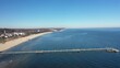 Aerial view - panning left turn with beach promenade coastline and Pier around city of Ahlbeck on the peninsula Usedom in Germany during a sunny day in early spring. Pier juts out into the Baltic Sea.