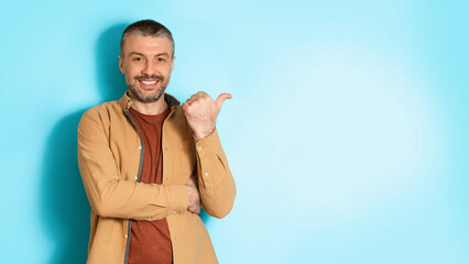 Poster - Man Pointing Thumb Finger Aside At Copy Space, Blue Background