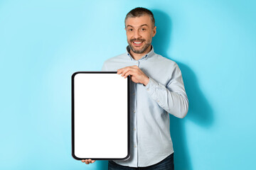 Poster - Middle Aged Man Holding Big Digital Tablet On Blue Background