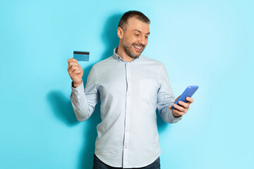 Poster - Happy Male Using Smartphone And Credit Card Shopping, Blue Background