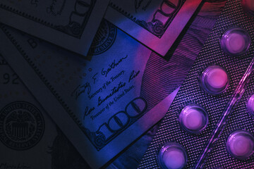 Poster - Pills or drugs and dollars cash money in a package under neon light on a dark background pattern for design..