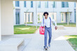 © javiindy - Positive black businessman riding skateboard in city