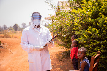 an African pediatrician visits child patients ready to be examined, wearing a face mask, a face shield and goggles to protect themselves during the pandemic