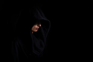 Young woman in profile in a black hoodie sweatshirt in the dark on a black background