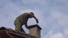 Repair Of The Chimney Pipe By A Worker On The Roof.