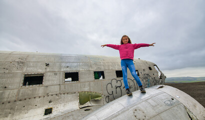 Canvas Print - Young tourist on the wings of an abandoned airplane wreck on the beach