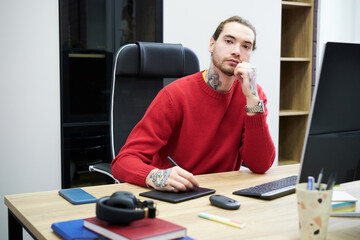 Poster - Portrait of young graphic designer looking at camera while sitting at table with computer and working on graphic tablet