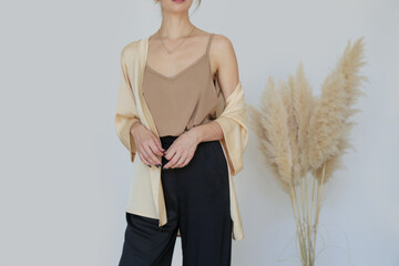Woman in beige silk kimono, camisole shirt and wide black trousers in the fashion atelier