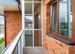 Small clean cozy glass balcony with windows city apartment red brick wall building