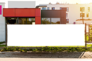 blank white advertising banner on the fence in front of modern residential buildings