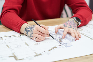 Poster - Close-up of architect drawing blueprint with pencil and ruler at table