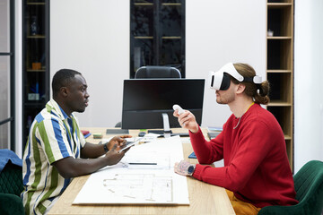 Poster - Business colleagues sitting at table opposite each othe and using virtual reality goggles at their work at office