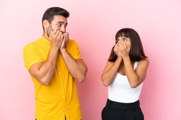 Wall Mural - Young couple isolated on pink background is a little bit nervous and scared putting hands to mouth