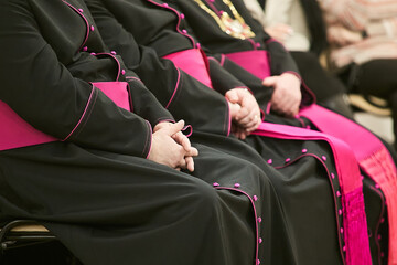 Priests or Bishops sit on a chair and hold their hands