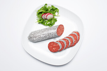 Top view of cutted smoked vegan sausage on the plate, on white background.