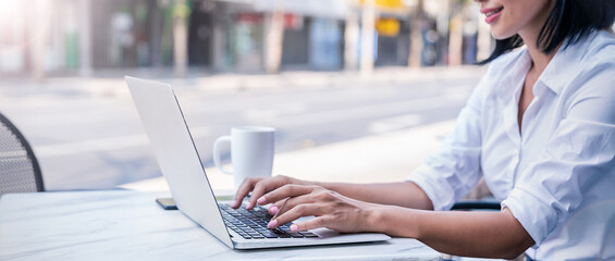 Closeup business woman hand typing on notebook, work on laptop computer in outdoor cafe restaurant. Student lecturing while studying online internet course. Work on digital device panoramic banner