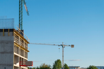 Wall Mural - Tower cranes on the construction site of modern apartment buildings. Sunny summer evening.