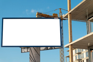  Blank white billboard for advertisement in front of the construction site. Residential ares with modern buildings on a sunny day