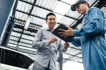 Wall Mural - Asian automotive mechanic explain car condition to client in garage. 