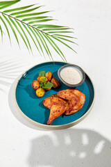 Poster - Roasted chicken with baked potato and creamy sauce on ceramic dish. Main course from chicken on white background. Simple food in minimalistic style. Golden chicken with potatoes.