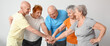 © Pixel-Shot - Happy elderly people in sportswear putting hands together on grey background