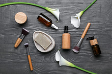 Composition With Cosmetic Products, Makeup Brushes And Calla Lilies On Dark Wooden Background