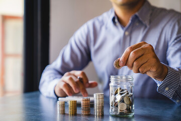 Wall Mural - Businessman putting coins in glass bottles saving bank and account for his money all in finance accounting concept, for saving money wealth, Savings for Retirement Planning