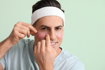 Sticker - Handsome man applying under-eye patch on color background, closeup