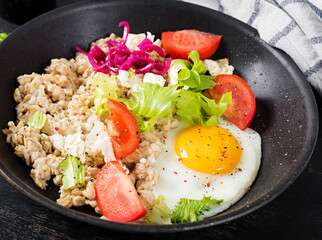 Breakfast oatmeal porridge with fried egg, tomatoes and lettuce. Healthy balanced food. Savoury oatmeal.