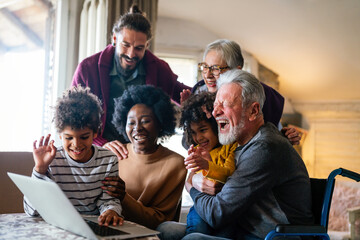 Wall Mural - Extended multiethnic family together at home during video call. People happiness technology concept