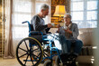 Mature man with disability in wheelchair spending time together with his wife at home