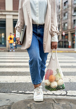 Businesswoman Walking At Street Holding Fruits In Mesh Bag