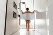 © Westend61 - Woman holding towel standing in bathroom