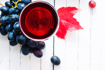 two glasses of red wine and grapes on white wooden table background