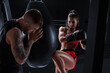 © andy_gin - Athletic woman in red shorts and top is boxing with a trainer. Boxing and mixed martial arts concept.
