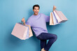 Photo of impressed millennial brunet guy hold bags yell wear sweater jeans isolated on blue color background