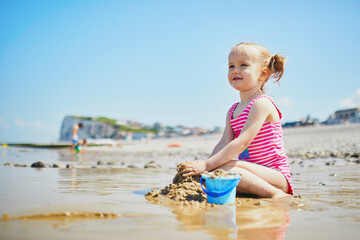 Poster - Toddler girl playing on the sand beach at Atlantic coast of Brittany, France