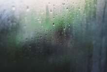 Water Droplets Of Humidity Condensation On Window Glass Seen From Indoor With Backyard Bokeh In The Background