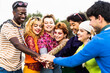 Happy young diverse friends having fun stacking hands together outdoor - Youth people millennial generation concept
