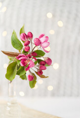 Poster - 
Glass vase with beautiful blooming rose branches, newspaper next to it. Light postcard background with bokeh.