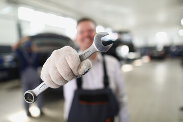 Wall Mural - Service worker hold wrench equipment, metal tool to fix vehicle