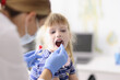 © H_Ko - Laboratory assistant in protective suit takes swab from childs throat, procedure at home