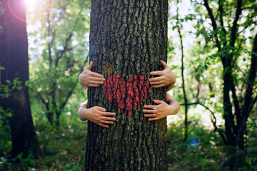 Family embracing the tree with red heart. Nature lover family.Concept of nature protection, care for environment. Environment day and earth day.