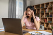 © Prostock-studio - Deadline stress. Young korean lady feeling tired after working on laptop, having headache and touching temples